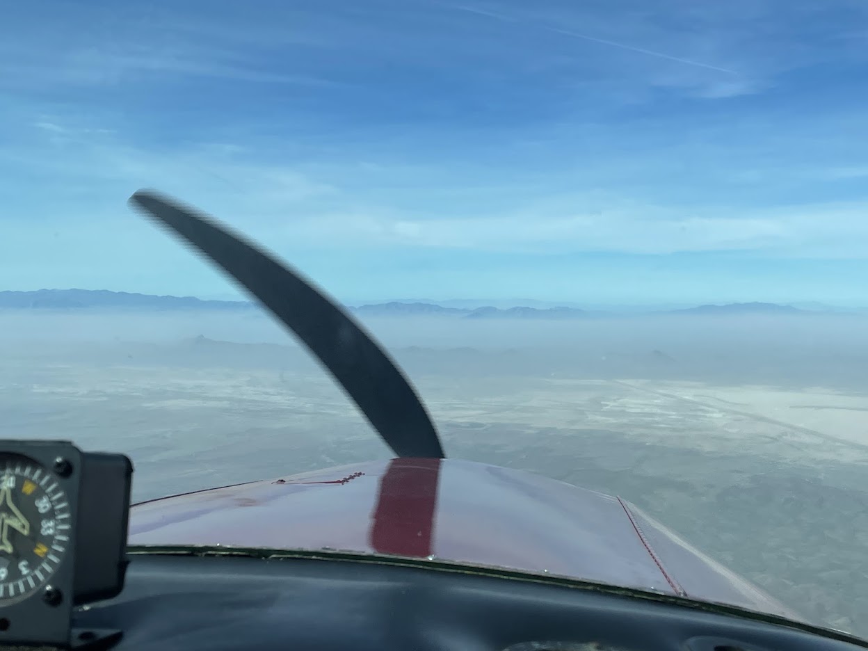 View over the airplane's nose toward a blue sky and distant mountains
